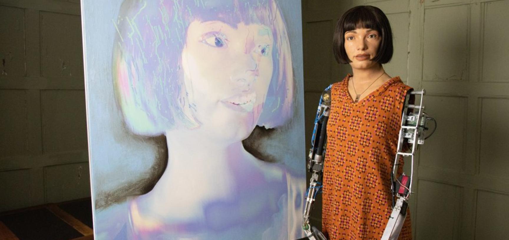 The AI-Da robot "artist" pictured in front of a self-portrait created by the AI