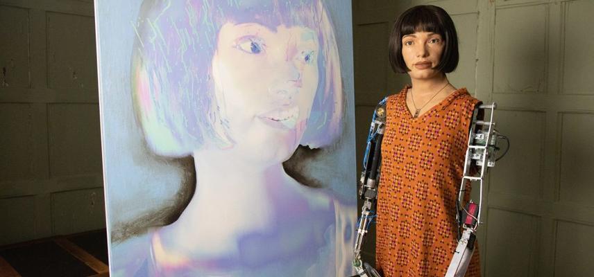 The AI-Da robot "artist" pictured in front of a self-portrait created by the AI
