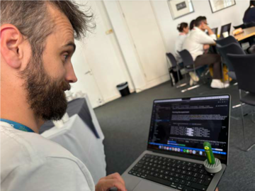 Federico Nanni looking at a laptop displaying white text on a black background