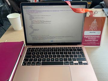 A laptop is open, showing TEI mark up text